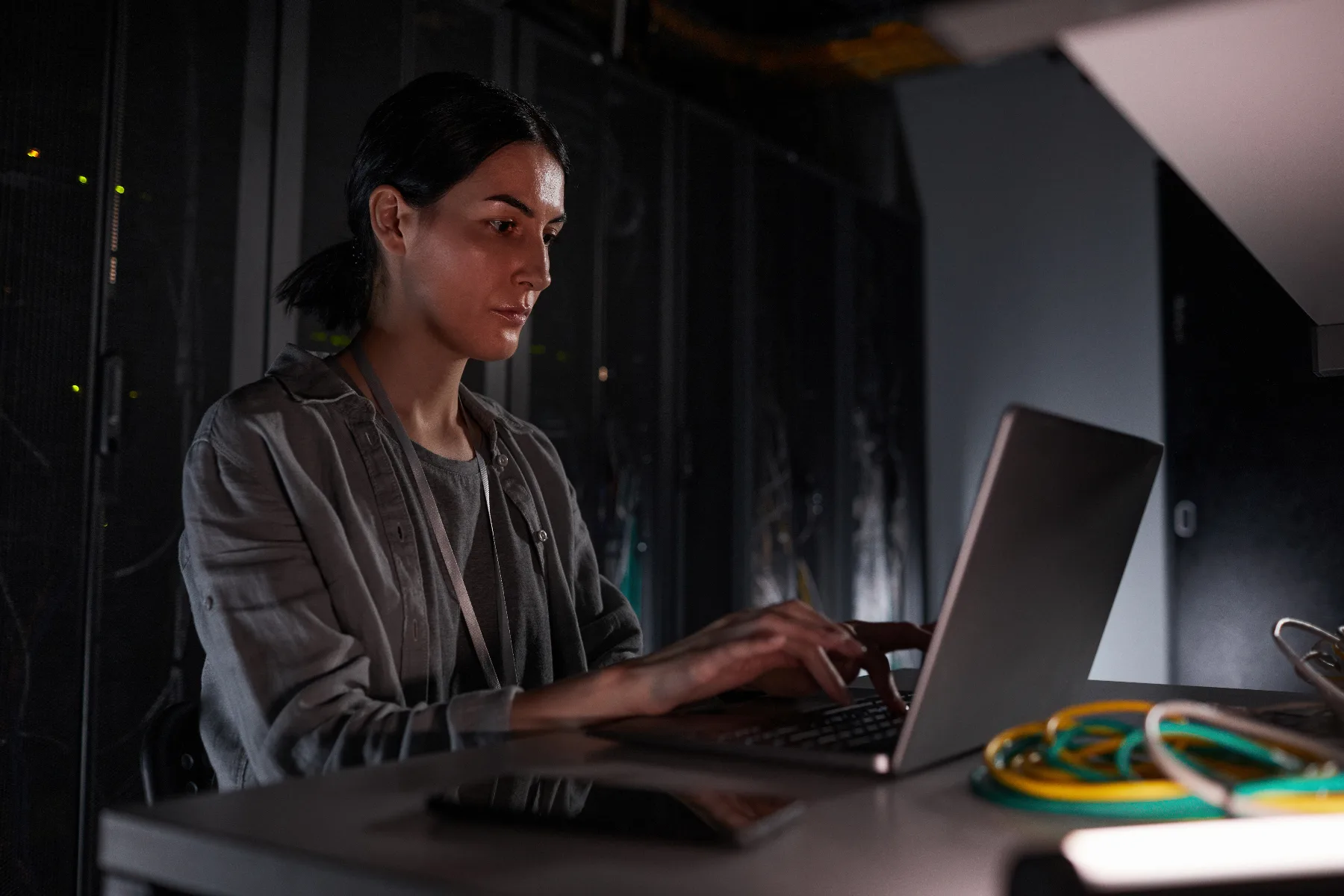 Techniker arbeitet abends an einem Laptop im Serverraum